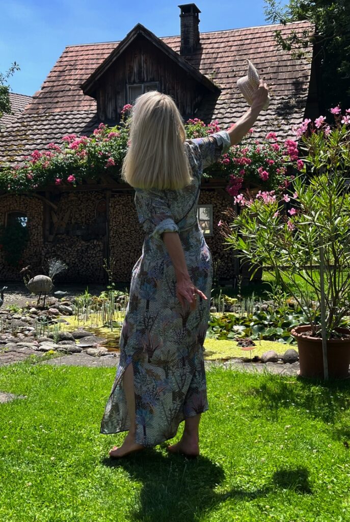 Frau mit langem Sommerkleid hell gemustert auf grüner Wiese