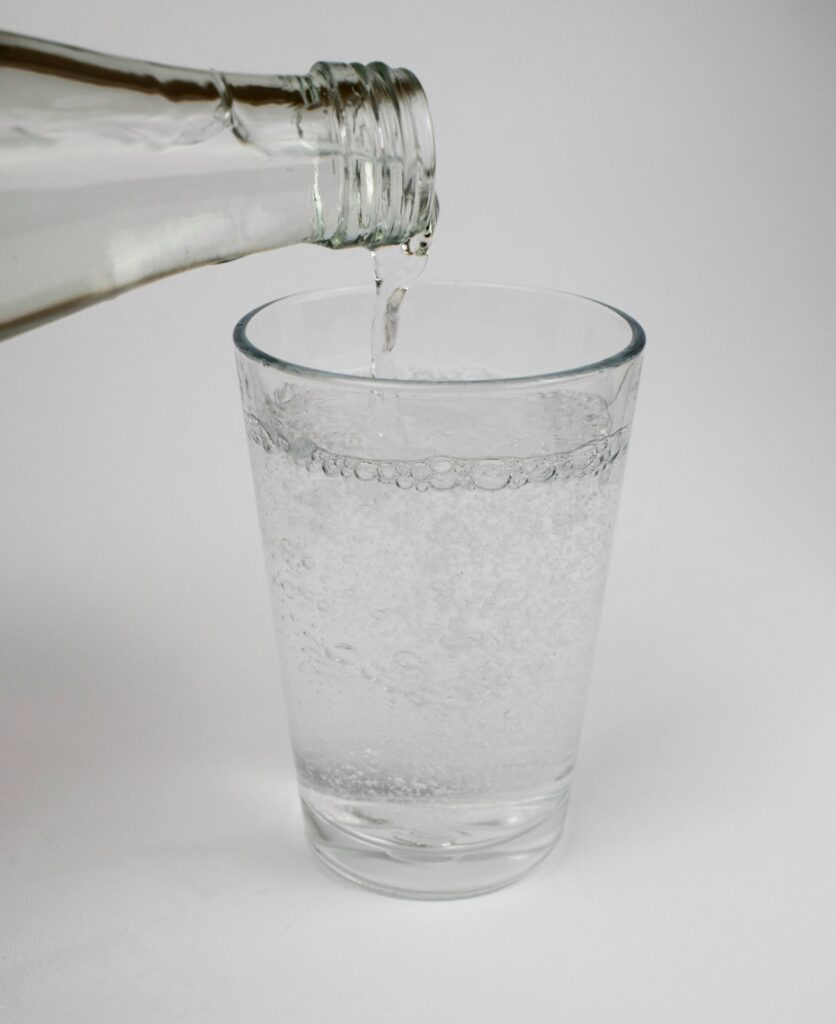Wasserglas gefüllt mit Mineralwasser und Flasche
