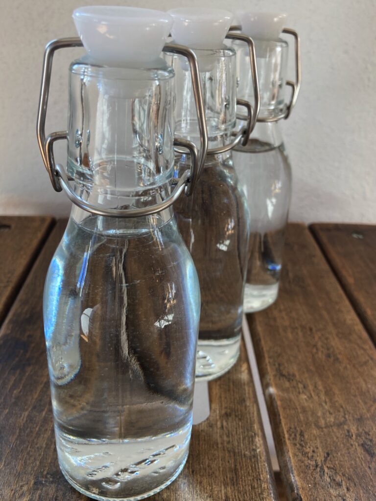 Drei gefüllte Wasserflaschen auf Holztisch