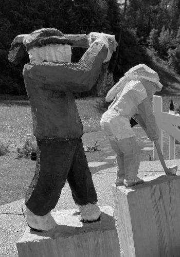 Zwei Holzfiguren ein Mann am Abschlag beim Golfen und eine Frau beim Putten